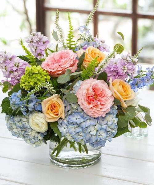 Blooming pastel hand-tied bouquet with soft pink, peach, blue, purple, and green blooms, ideal for scheduled GTA delivery.

